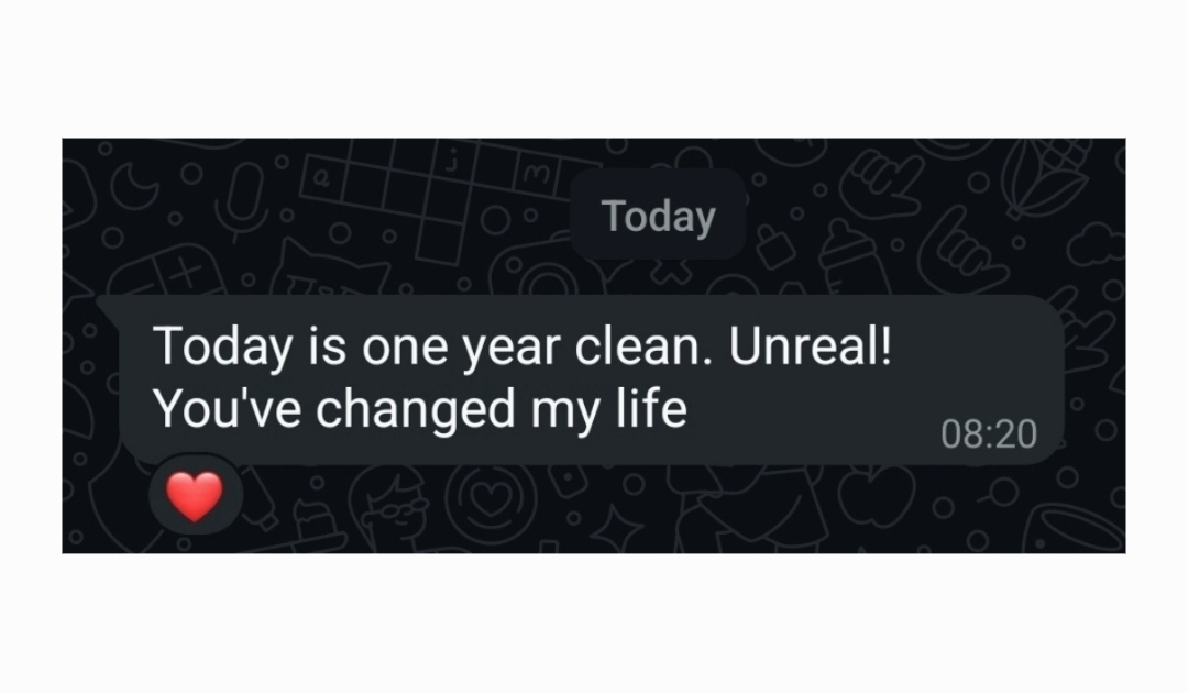 WhatsApp message from a client: “Today is one year clean. Unreal! You've changed my life”, with a heart reaction.